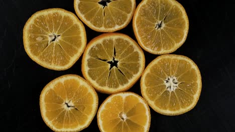 collection of fresh mandarin slices on black background. rotation citrus fruit. top view.