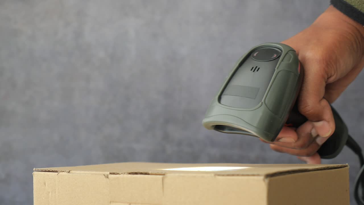 Hand Scanning Barcode on Cardboard Box with Scanner