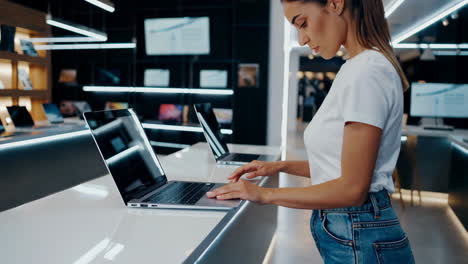 woman browsing laptops in a modern electronics store