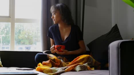 Front-view-of-young-asian-woman-having-coffee-in-living-room-at-home-4k