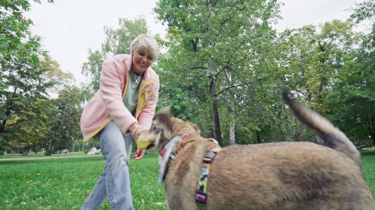 Happy Woman Playing Tug-of-War with Dog in Public Park