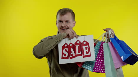 happy man showing sale word inscription, smiling, looking satisfied with low prices. slow motion