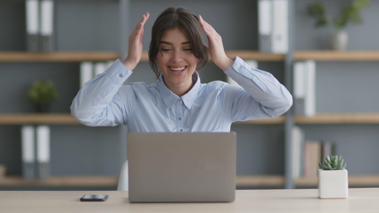 mujer celebrando el éxito en la computadora portátil en la oficina