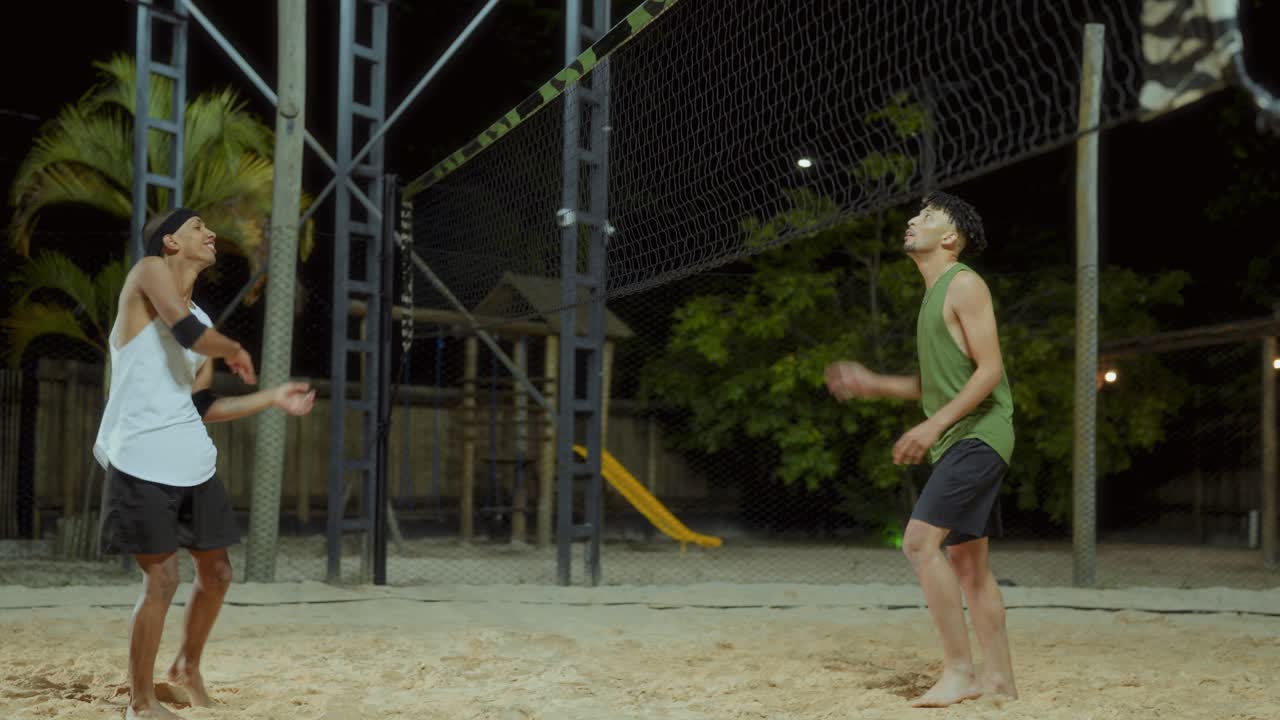 Two Men Playing Beach Volleyball at Night