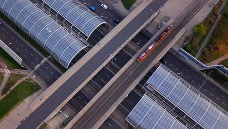 electric tram crossing through a bridge, trasa torunska motorway highway with soundproof glass panels roof, road intersection, warsaw city traffic, overhead aerial view