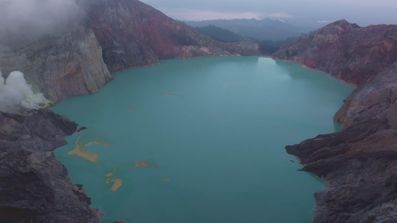 Gesluierd kratermeer glinsterend onder de mistige bergkammen van Ijen, Indonesië