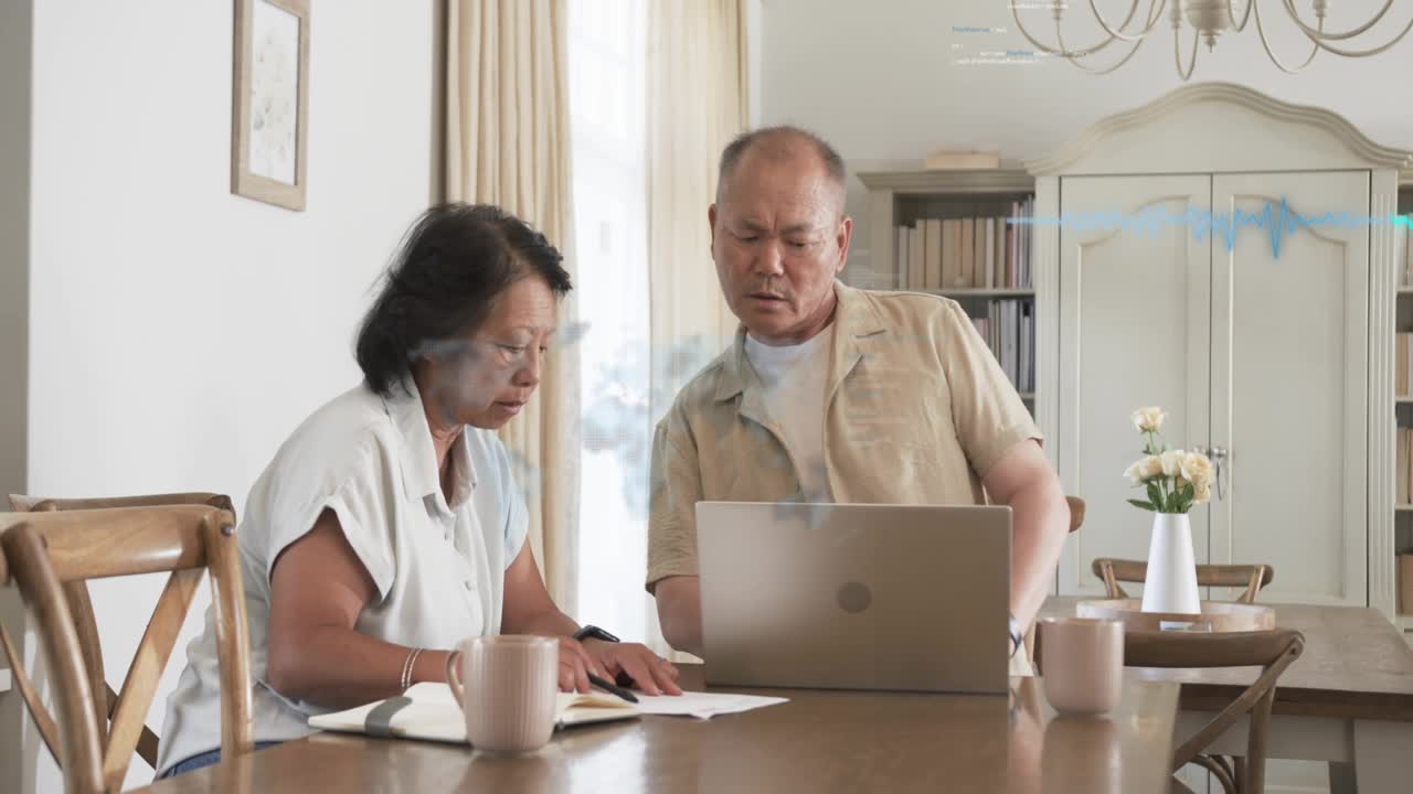 Mature man and senior woman reviewing finances at dining table, HUD appearing after pointing