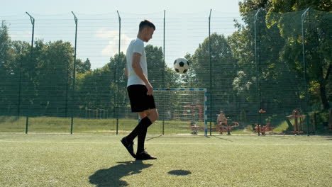 a young soccer man training freestyle tricks with the ball on a street football pitch on a sunny day 2