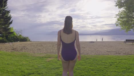 Rear-view-of-attractive-girl-walking-toward-sandy-mountain-beach