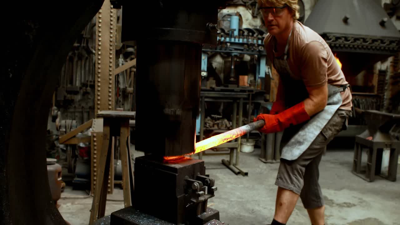 herrero moldeando varilla de metal caliente en la máquina 4k