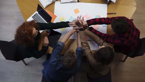 European-happy-team-of-business-people-students-stack-hands-in-pile-together-as-teamwork-and-help,-friendship-concept,-support-in-group-work,-unity-trust-cooperation.-Footage-from-above.-Slow-motion