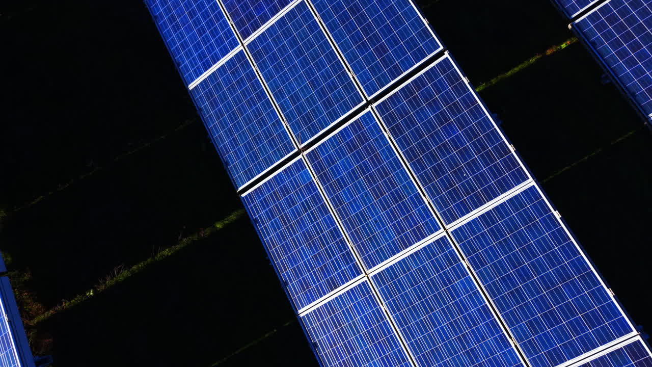 Vista aerea ravvicinata di celle solari blu con linee della griglia visibili e strutture di montaggio metalliche. Dettaglio della superficie e del telaio dei moduli solari fotovoltaici.