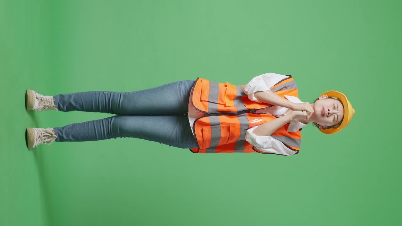 Full Body Of Asian Female Engineer With Safety Helmet Pray For Something While Standing In The Green Screen Background Studio