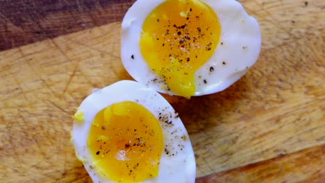 healthy breakfast hard boiled eggs on a wooden cutting - salt and pepper - top down spinning