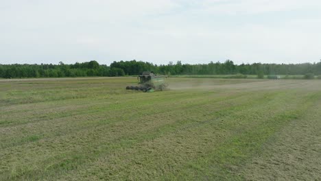 Aerial-establishing-view-of-combine-harvester-mowing-yellow-wheat,-dust-clouds-rise-behind-the-machine,-food-industry,-yellow-reap-grain-crops,-sunny-summer-day,-wide-drone-dolly-shot-moving-left