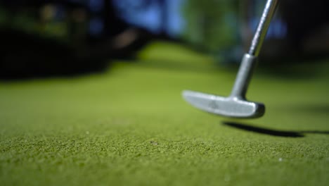 Pelota-Amarilla-De-Minigolf-Con-Un-Bate-Cerca-Del-Hoyo-Al-Atardecer