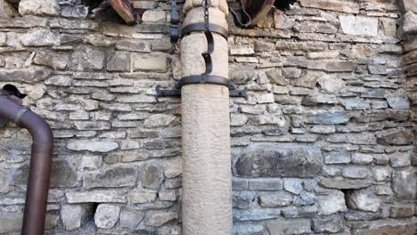 white stone pillory with black iron shackles mounted to castle walls. a heavy chained sphere lies below. historic slovak setting evoking medieval justice, punishment, and architectural heritage