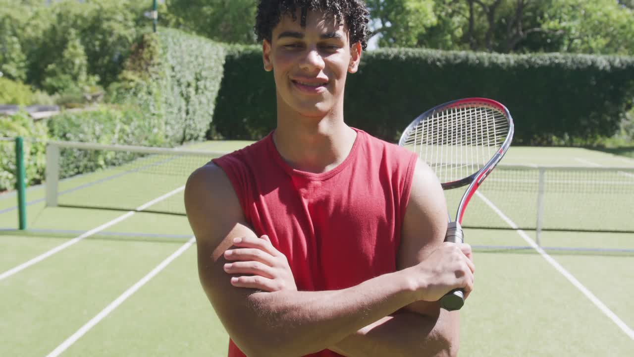 Portrett av en glad birasial mann med tennisracket i hagen på en solrik dag