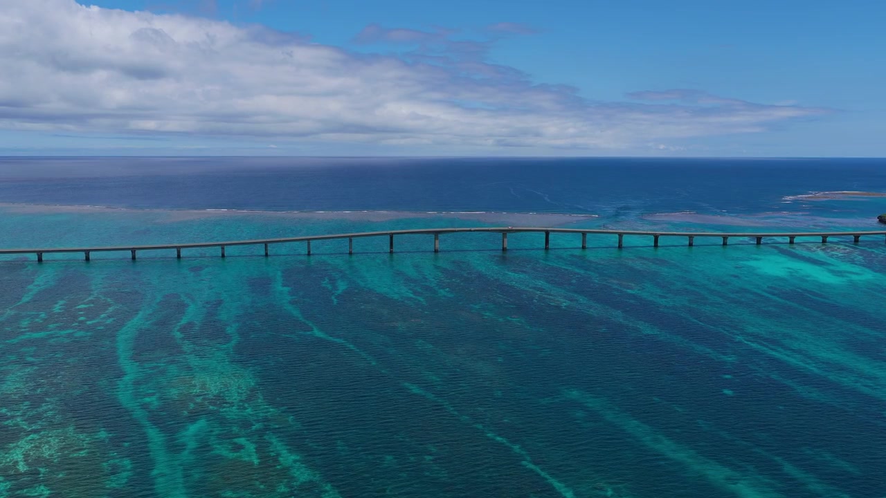 Inquadratura orizzontale con carrello in avanti verso il Ponte Kurima, sopra le acque costiere turchesi vicino al porto peschereccio di Miyako, Okinawa, Giappone