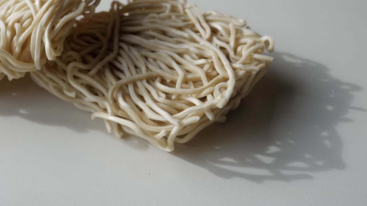 Wheat noodles scattered, highlighting the texture and shadows on a surface