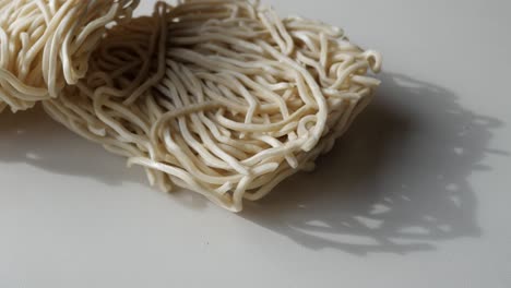 wheat noodles scattered, highlighting the texture and shadows on a surface