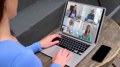 mujer caucásica usando una computadora portátil en una videollamada con colegas que trabajan desde casa