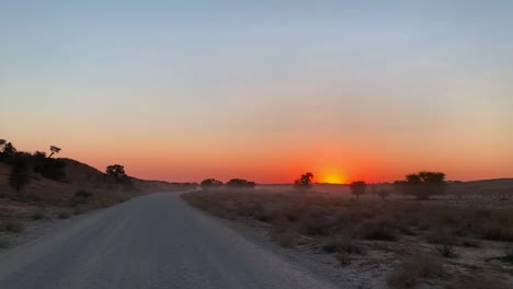 a point of view of a driving vehicle with the beautiful sunrise on the horizon, kalahari desert