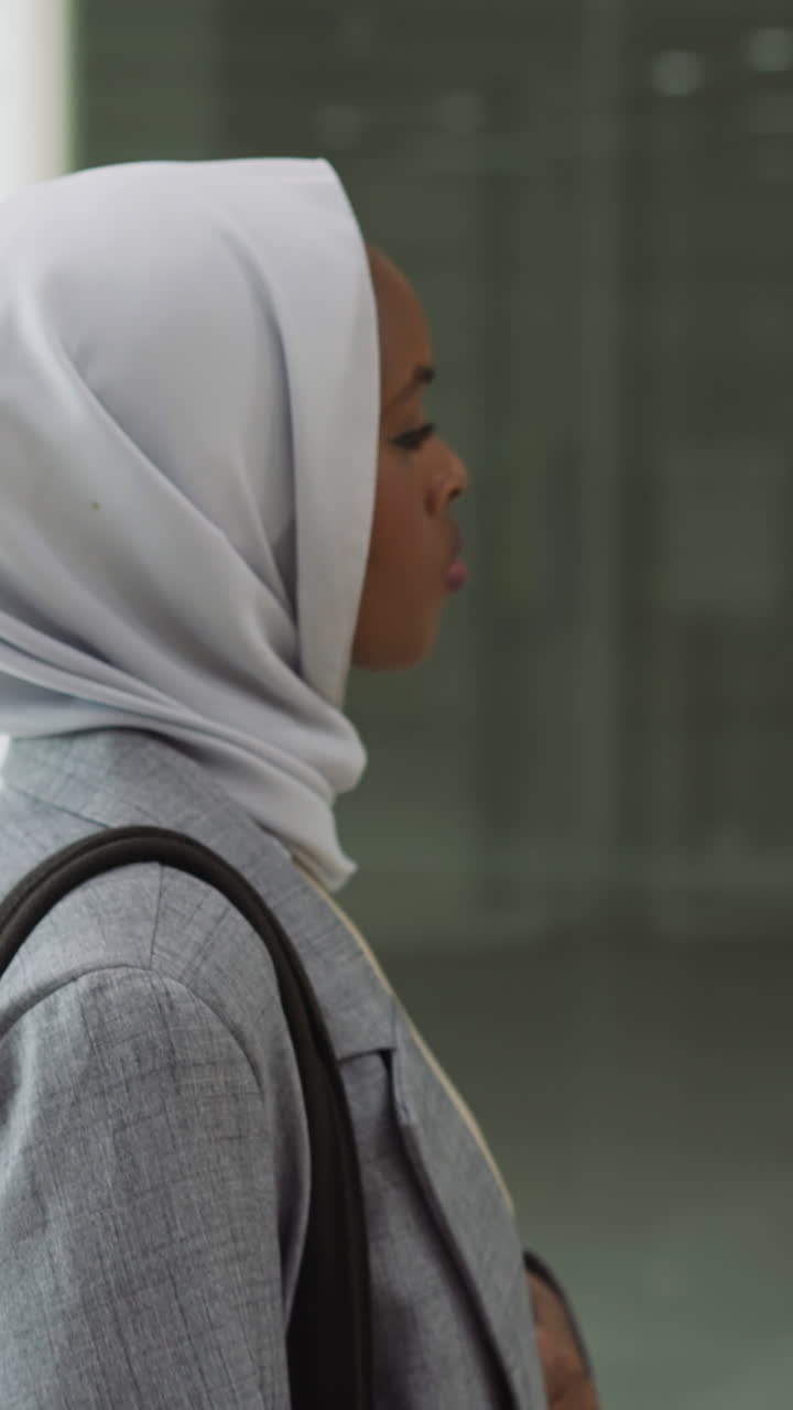 Young black woman in hijab looks around with confused sight in shopping mall slow motion. Muslim lady choose store to visit in mall. Arabic country lifestyle
