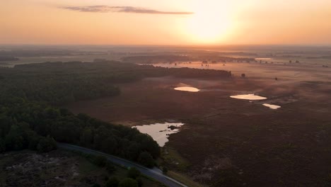 aerial view of a misty landscape with lakes and forest at sunrise or sunset