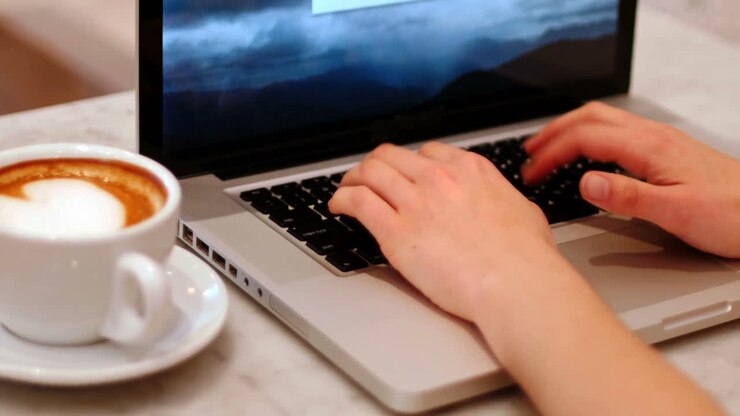 Woman with cup of coffee using laptop on table