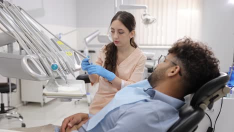 a dedicated brunette male dentist in a crisp white coat attentively interacts with his blond caucasian patient, who is comfortably seated in a sleek, modern dental chair. the bright, airy office is illuminated by soft natural light, enhancing the high-tech dental equipment that glows reassuringly, c