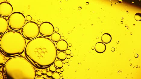 burbujas de aceite en la superficie del agua en movimiento, sobre un fondo amarillo, macro, pantalla de inicio, plantilla, espacio de copia