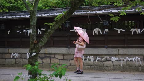 young japanese girl walking through temple with umbrella, early summer kyoto