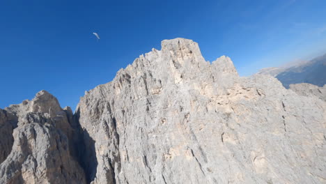 paragliding in blue sky over high rocky peaks of dolomites mountain range