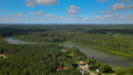 Flying-over-Kowalskie-Blota-village-daytime,-many-private-houses,-and-cottages-located-on-the-bank-of-Okierskie-lake,-Poland,-panning-around-movement