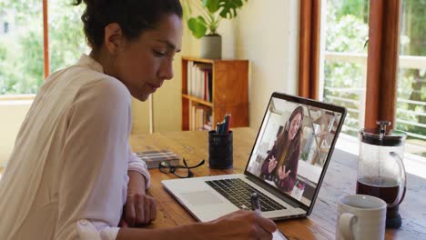 mixed race businesswoman sitting at desk using laptop having video call with female colleague
