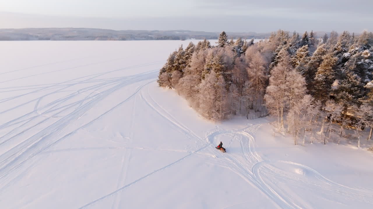 Vista aerea di una motoslitta che guida sul ghiaccio, nelle regioni lacustri artiche della Finlandia