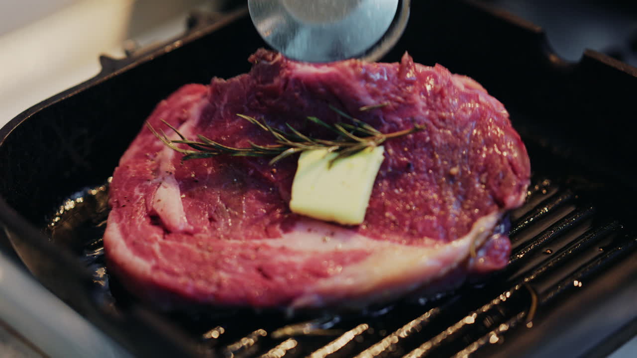 Close up of a juicy steak being moved with a spatula on a hot grill pan