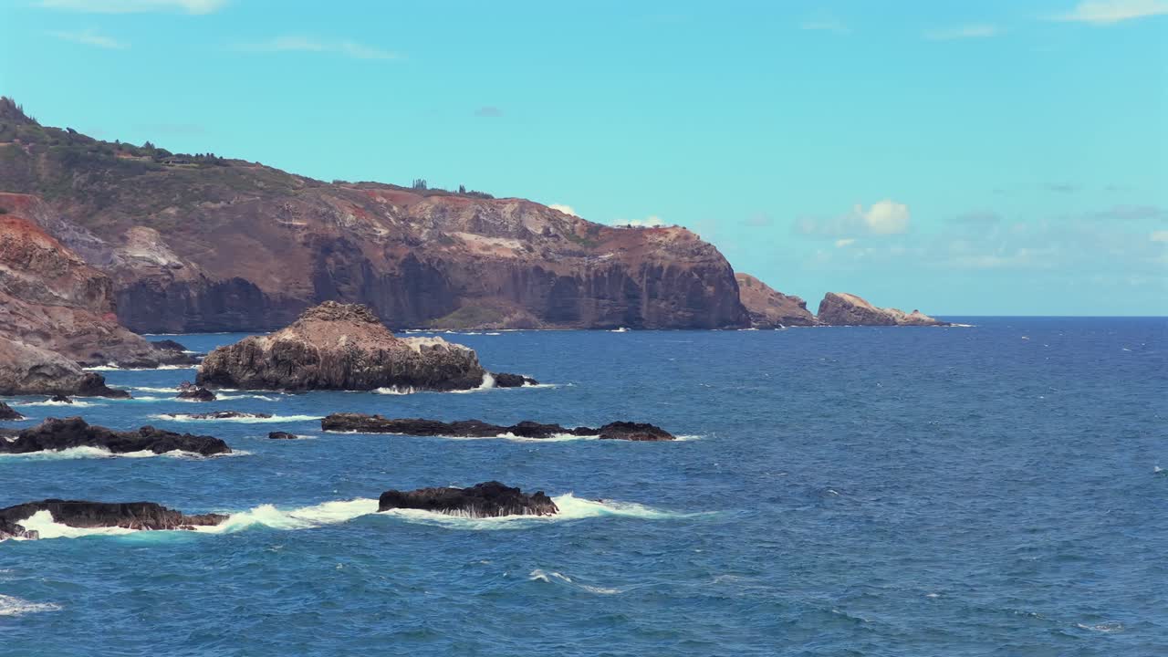 Drone pans across a rocky Hawaiian shore rarely seen by visitors, revealing epic cliff faces in close up with dramatic panning camera movements. Perfect for adventure tourism and establishing shots