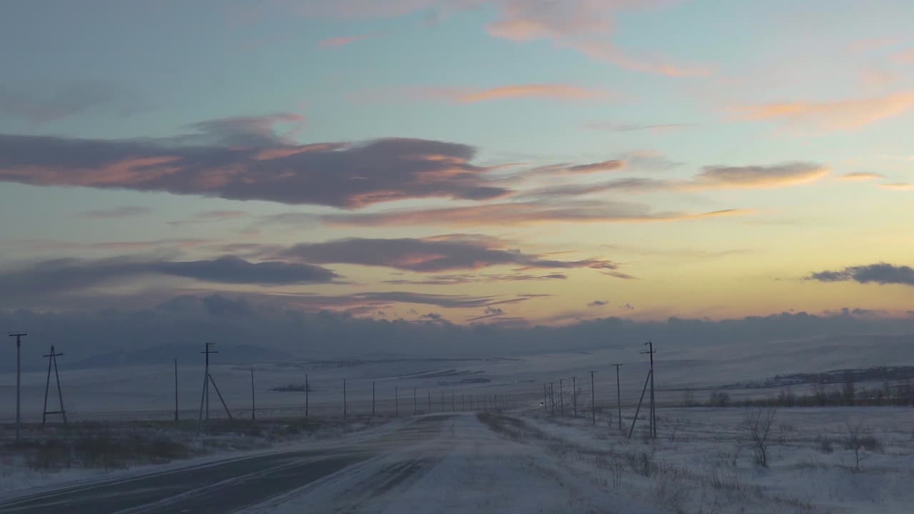 hermosa puesta de sol sobre un campo nevado con una larga carretera en primer plano