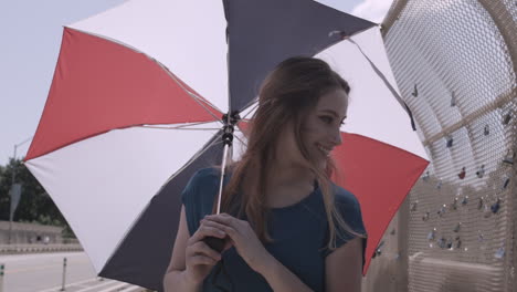 Front-view-of-a-woman-twirling-her-umbrella-as-she-walks-across-a-bridge-in-the-city