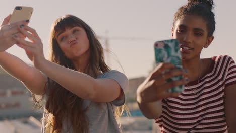 beautiful young women friends taking selfies using smartphone enjoying hanging out on rooftop at sunset ready for weekend party