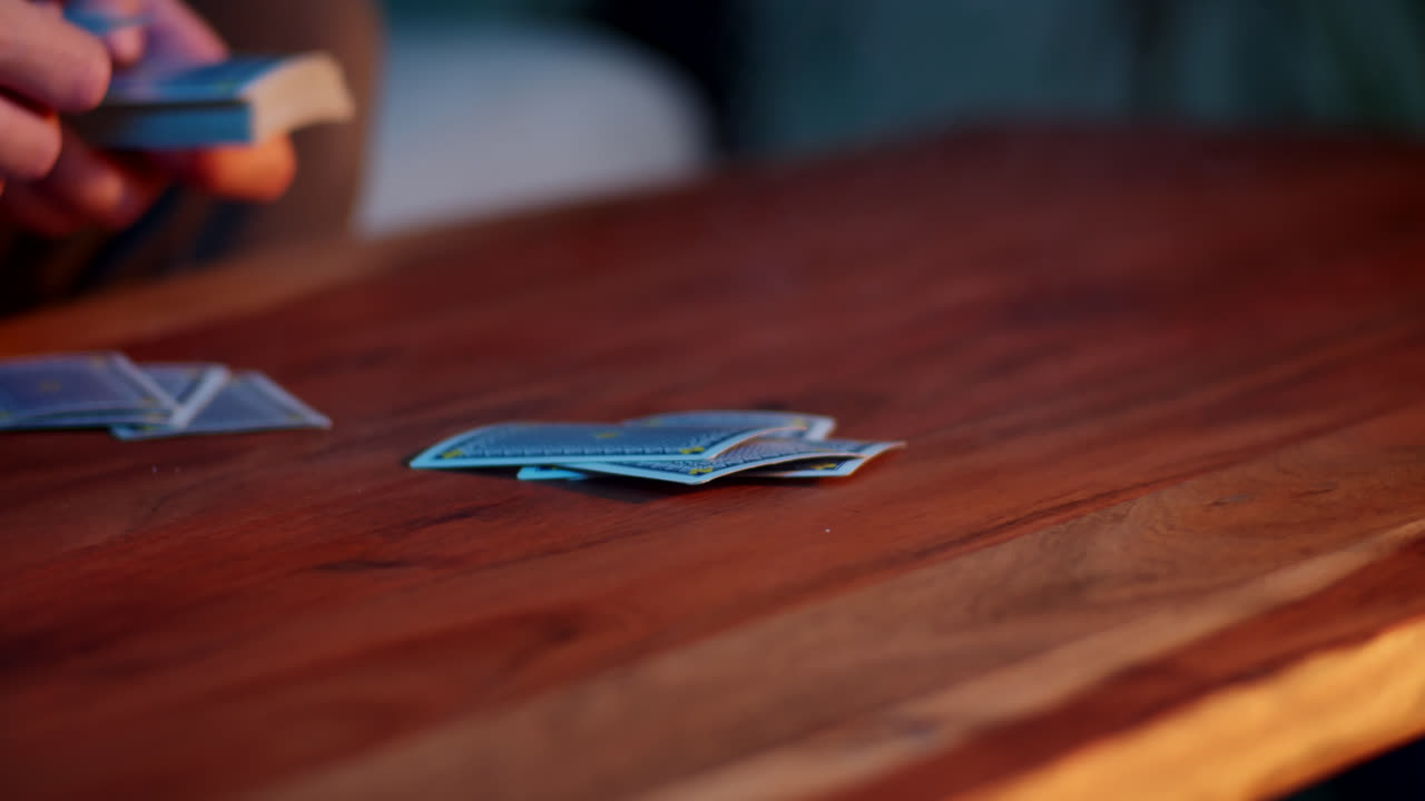 Person playing card game at a wooden table
