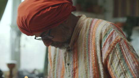 indian man in kurta kneading dough in metal bowl on wooden kitchen table