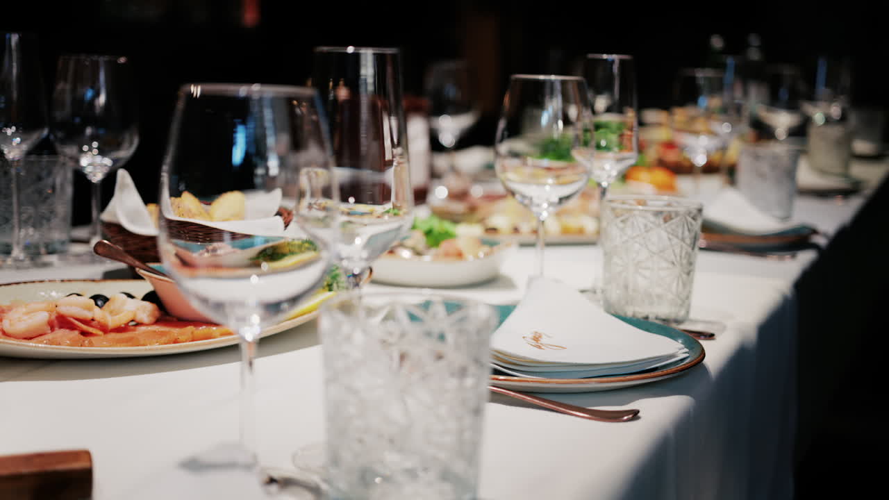 Refined restaurant table setting with crystal glasses, plates, and gourmet dishes in the background