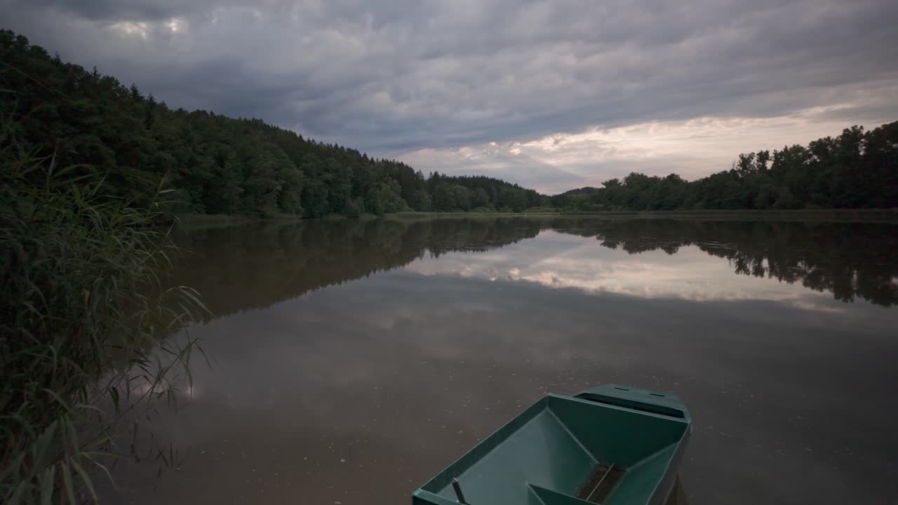 Serene Lake with a Green Boat Under a Cloudy Sky
