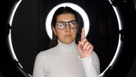 mujer con gafas sobre iluminación blanca en negro