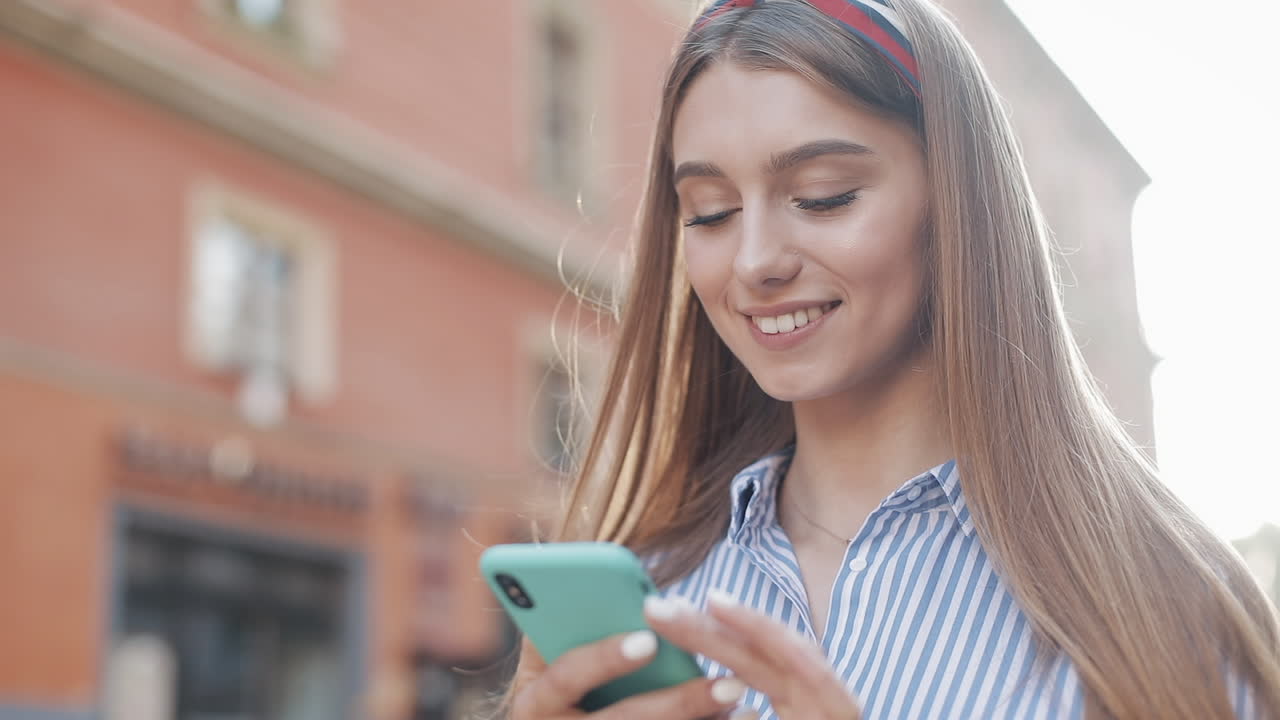 Giovane donna felice sorridente che invia messaggi sullo smartphone all'aperto