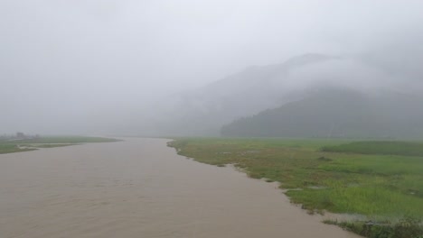 站在大雨中的一座桥上看着尼泊尔季风期间洪水泛滥的河流