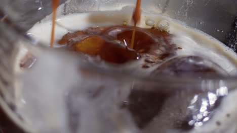 coffee being poured into a glass with ice